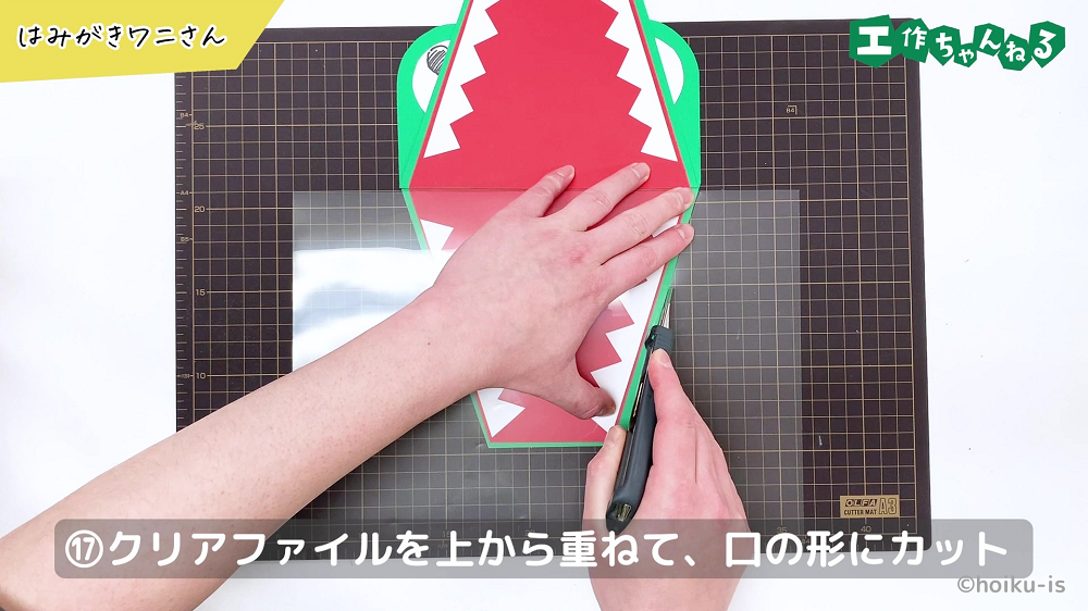 ワニの口に沿ってクリアファイルをカットしている手元