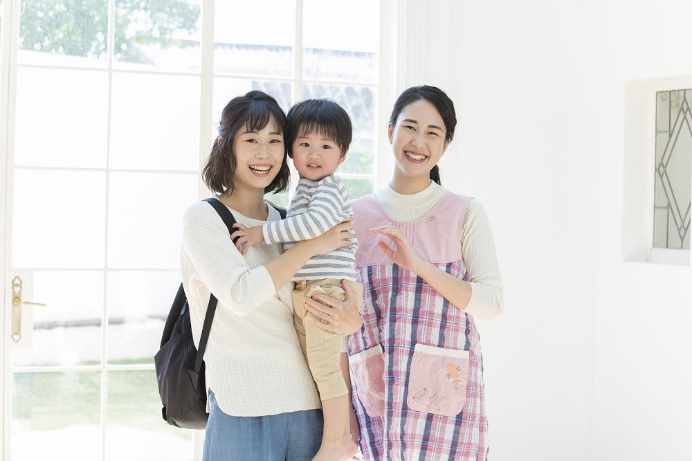 笑顔の保育士、保護者、子ども