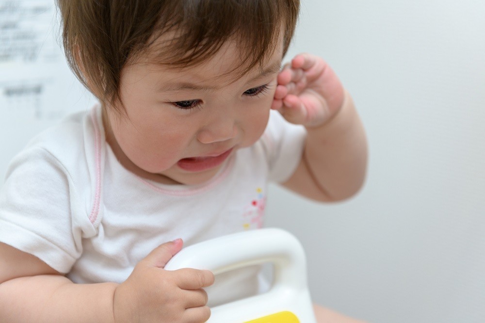 便座にまたがってトイレトレーニング中の子ども