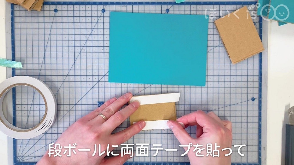 段ボールに両面テープを貼っている場面