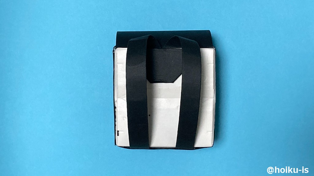 19、残りの折り紙を三つ折りにし、端を2カ所三角に折り、上下に両面テープをつけて貼る。