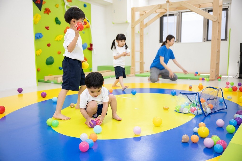 保育室内でボールを使って遊ぶ子どもたち