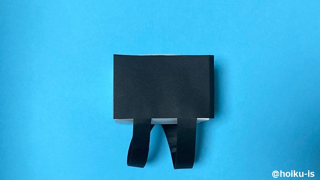 10、半分に切った折り紙を、牛乳パックに合わせて切り、両面テープを貼る。