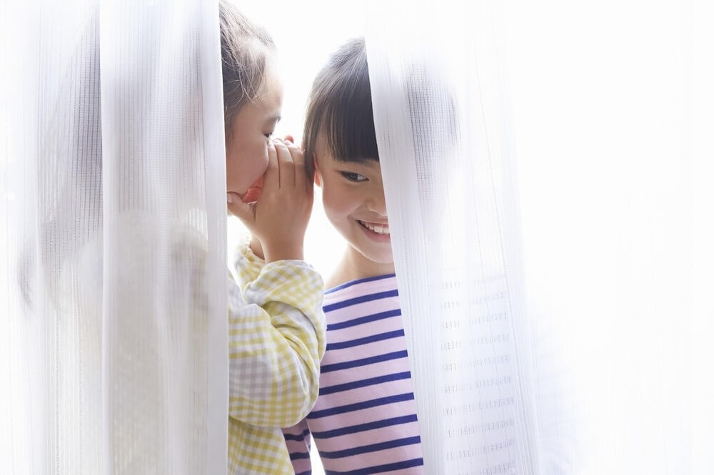 カーテンの陰でひそひそ話をする子どもたち