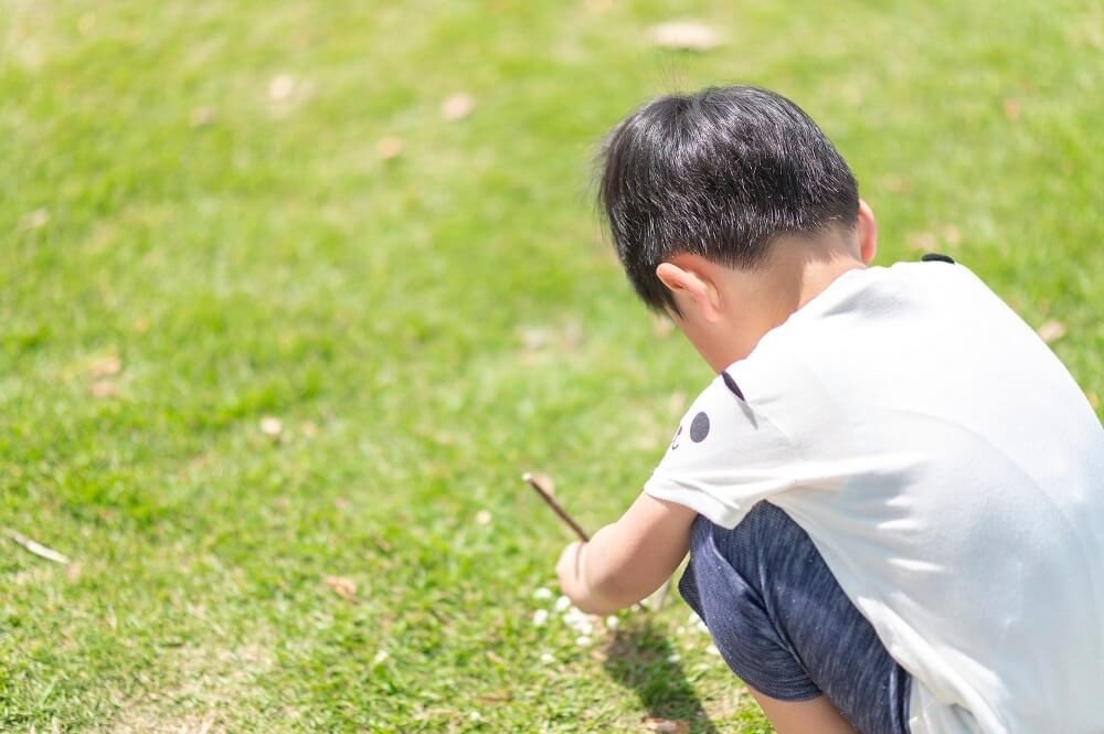 草の上でしゃがんでいる子ども