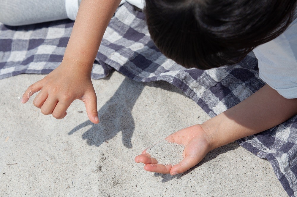 手で砂を救っている子ども