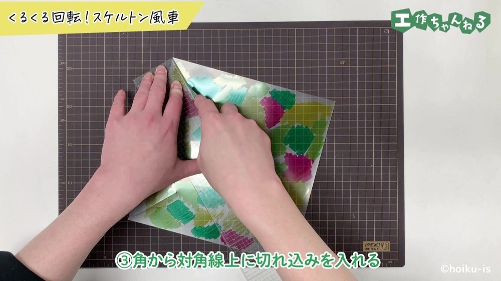 カッターでクリアファイルに切れ込みを入れている手元