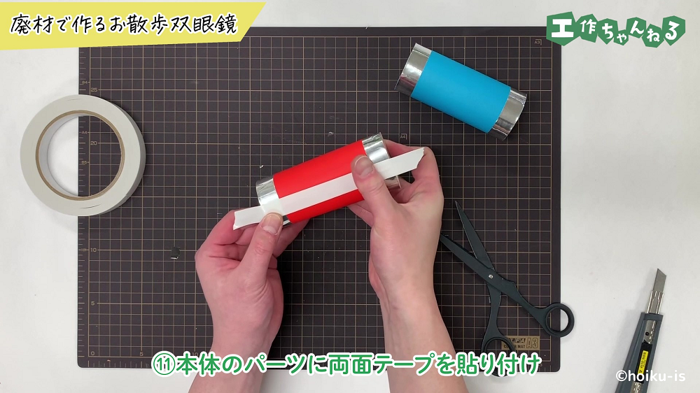 双眼鏡のパーツに両面テープを貼り付けている手元