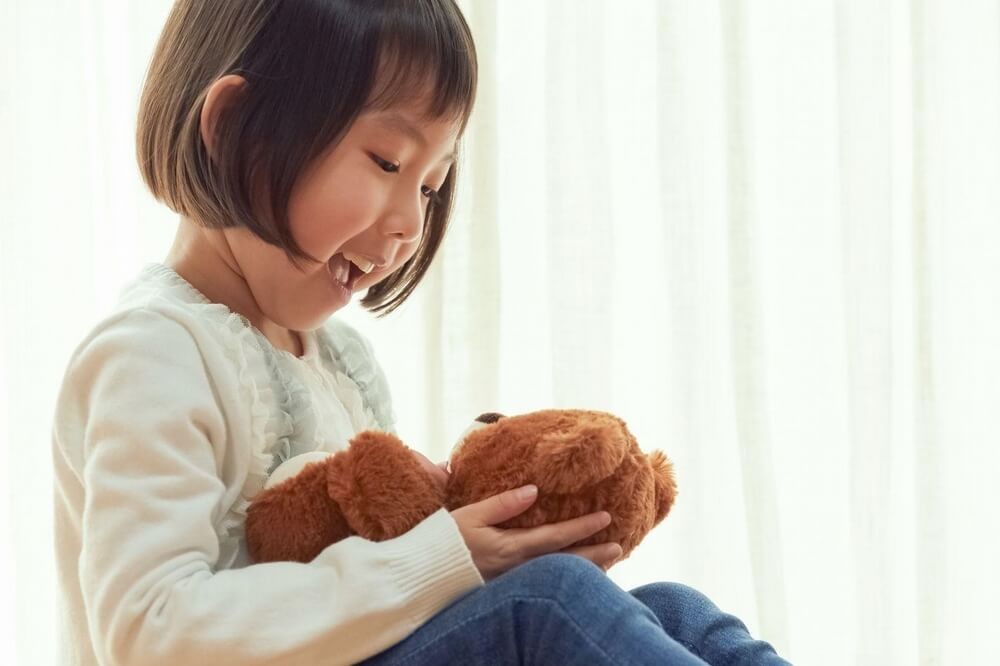 くまのぬいぐるみに話しかける女の子