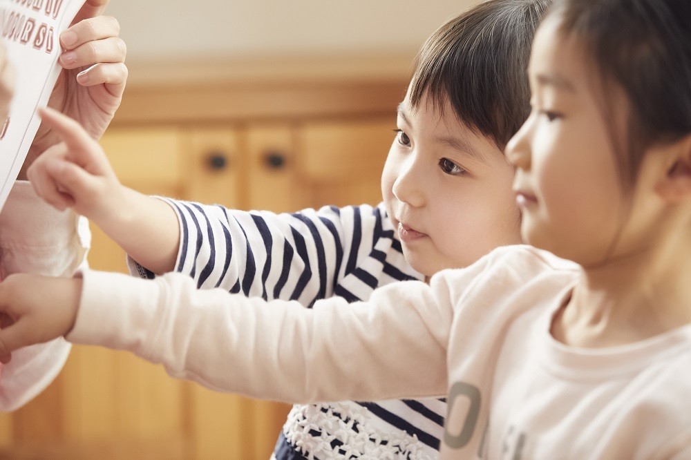 英語の本を指出している2人の子ども