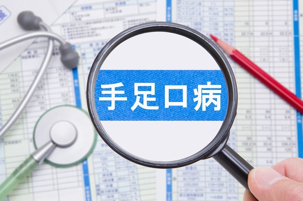 虫眼鏡で拡大された「手足口病」の文字