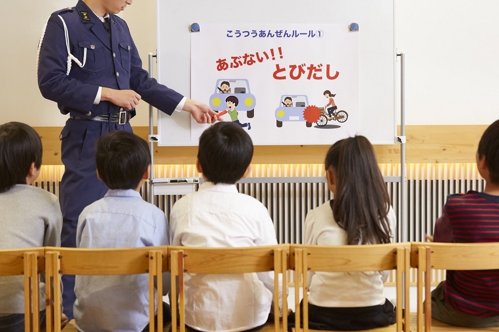 警察官による交通安全指導のホワイトボードを見ている子どもたち