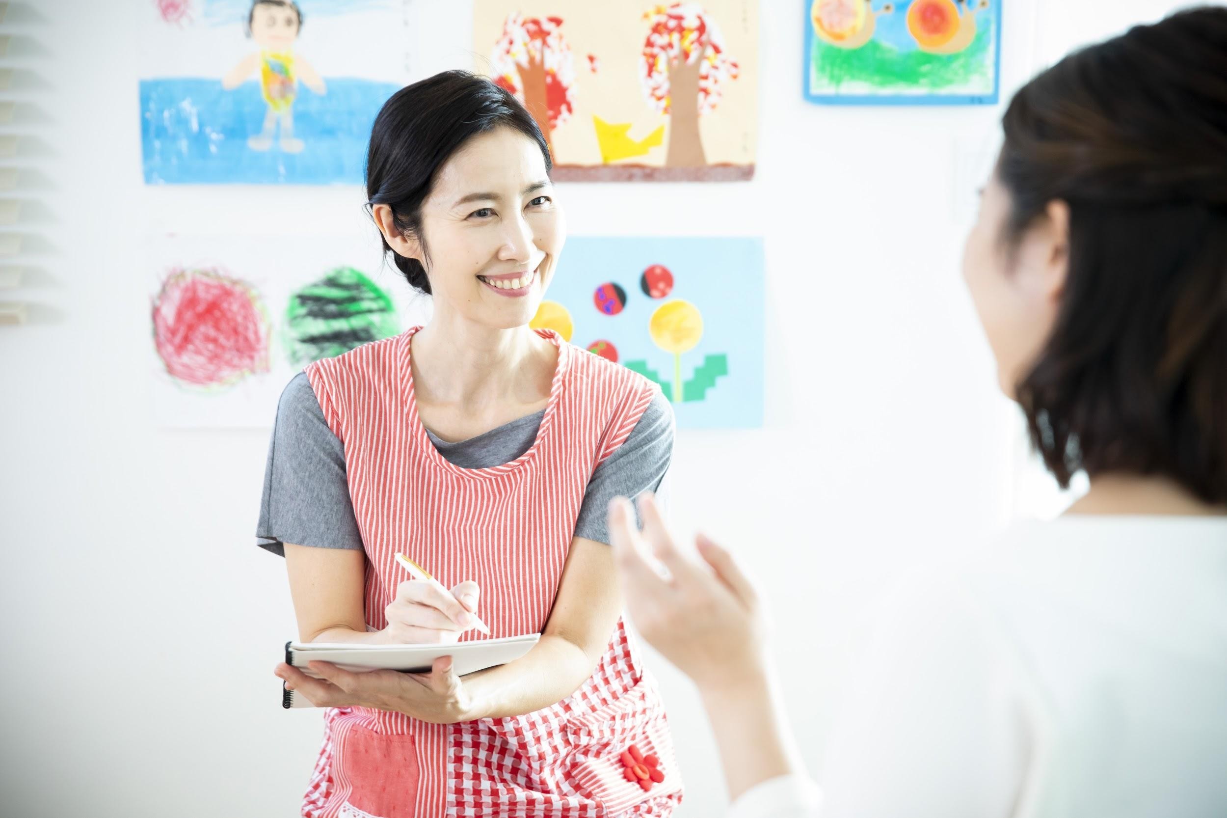 保護者の話しをメモしている保育士