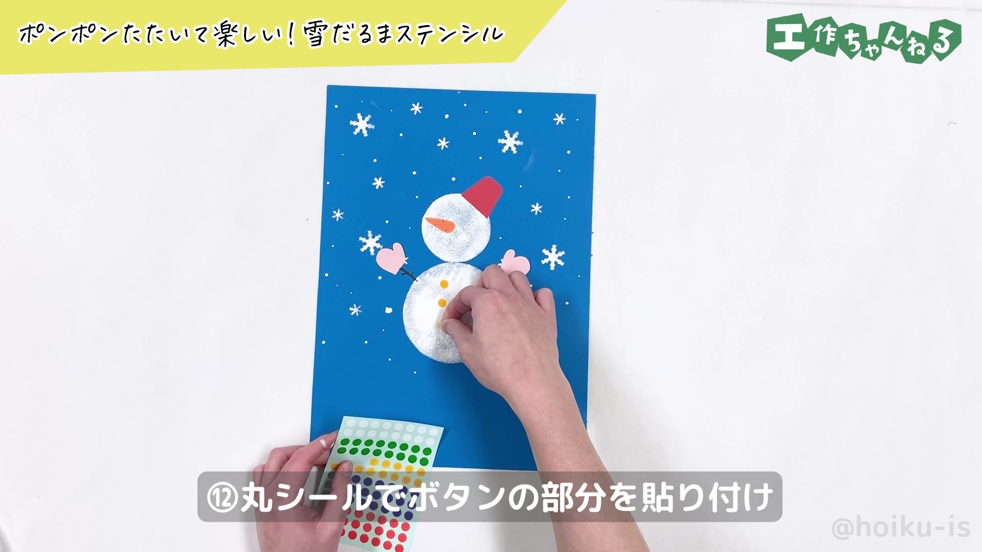 雪だるまのボタン部分に丸シールを張り付けている様子