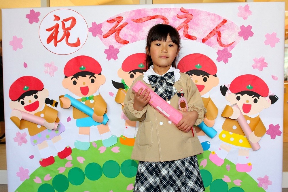 卒園証書を持って記念撮影をする女の子