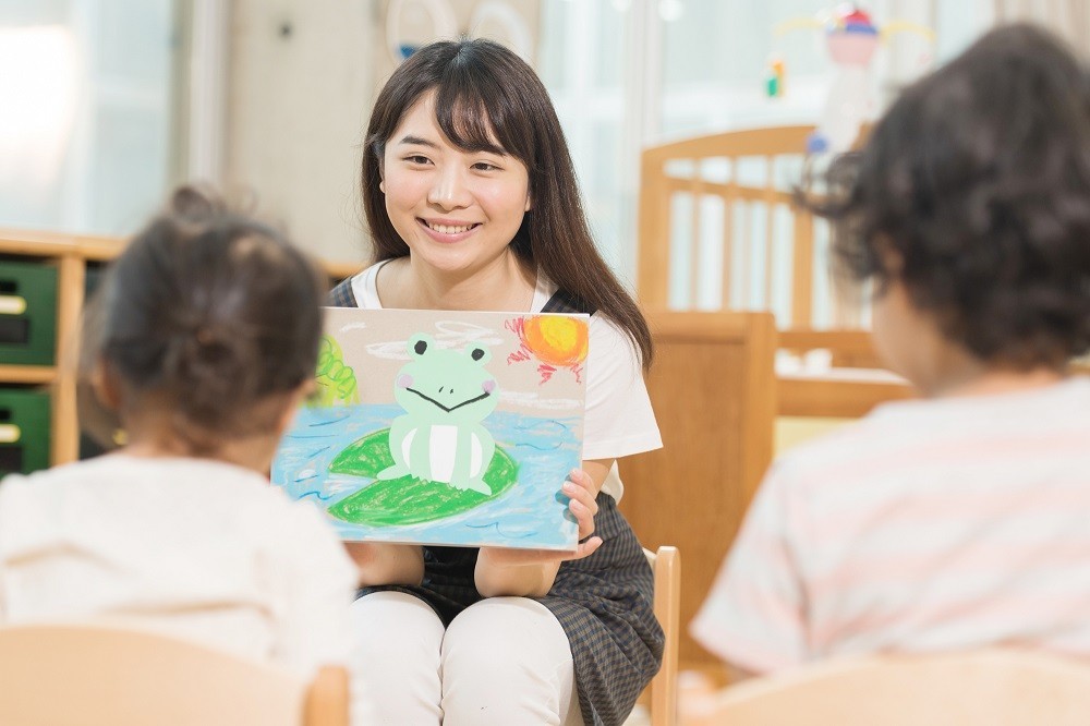 子どもたちに読み聞かせをしている保育士