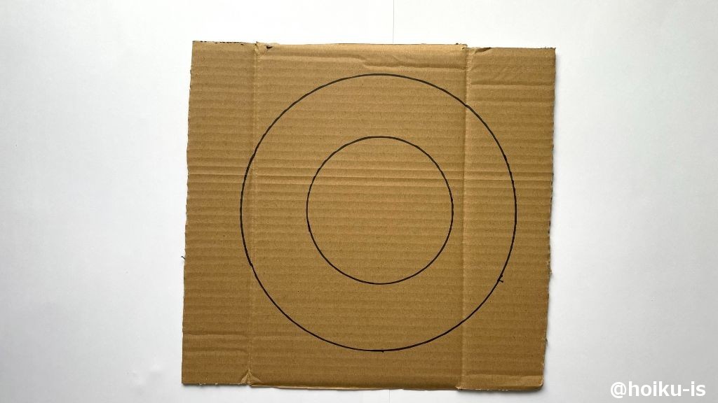 ダンボールにお皿などの丸いものやコンパスで、大小2つの円を描く