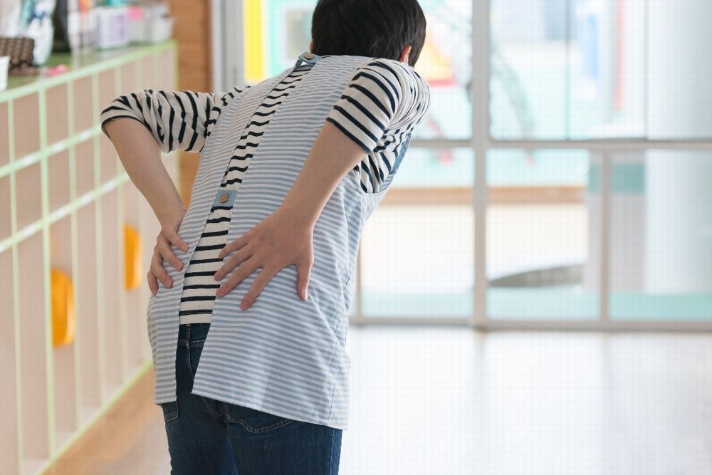 腰の痛みを気にする保育士