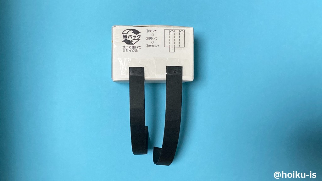 8、牛乳パックの底を手前に置き、テープで肩ひも2本を貼り付ける。