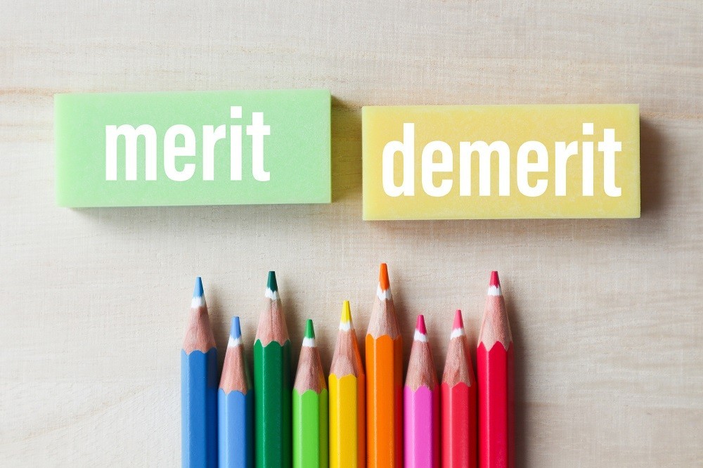「merit」「demerit」と書かれた消しゴムと色鉛筆