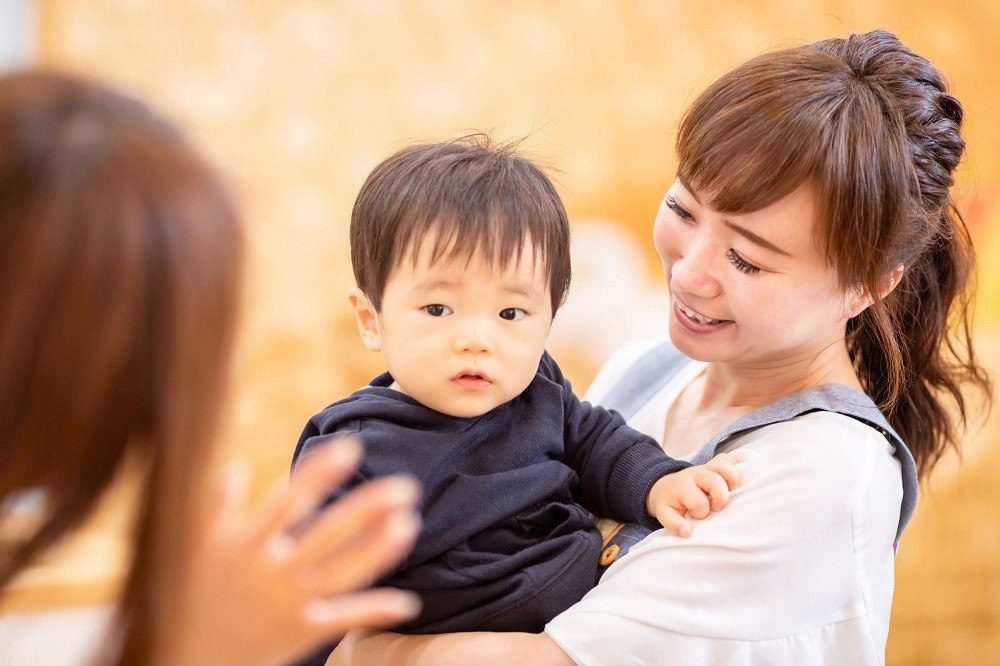 子どもを抱っこする保護者