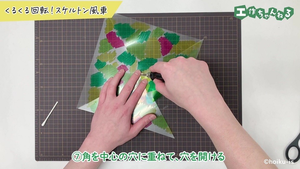 クリアファイルの角に穴を空けている手元