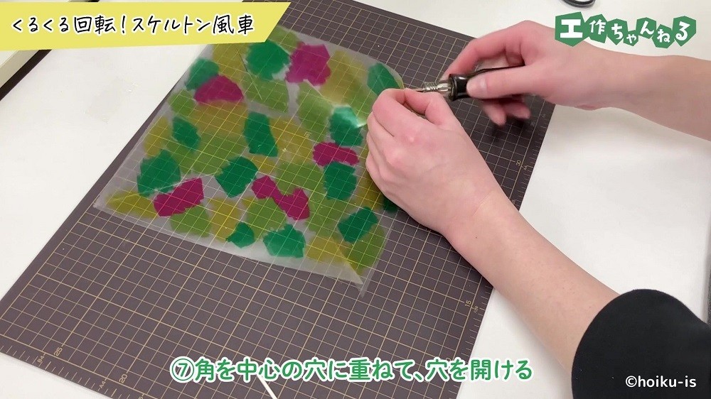 クリアファイルの角に穴を空けている手元