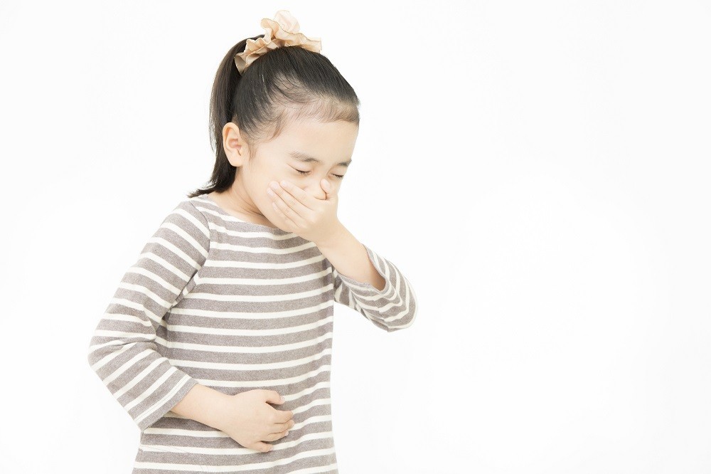 口元とお腹を押さえている女の子