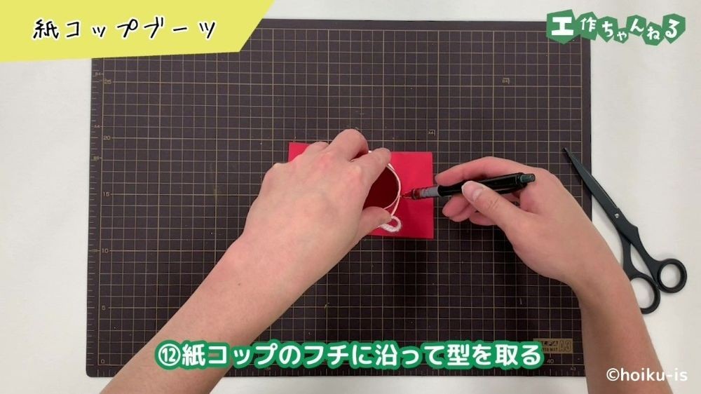紙コップのフチに沿って型を取っている手元