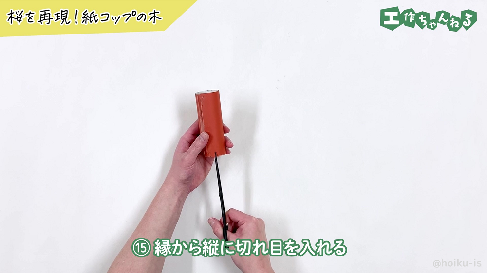 トイレットペーパーの芯の縁に切れ込みを入れている様子