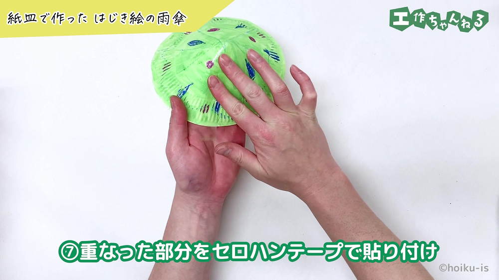 色を塗った紙皿にセロハンテープを貼り付けている手元