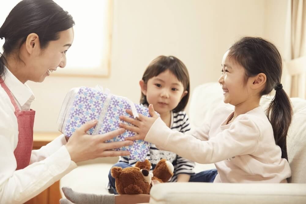 保育士さんにプレゼントを渡す女の子