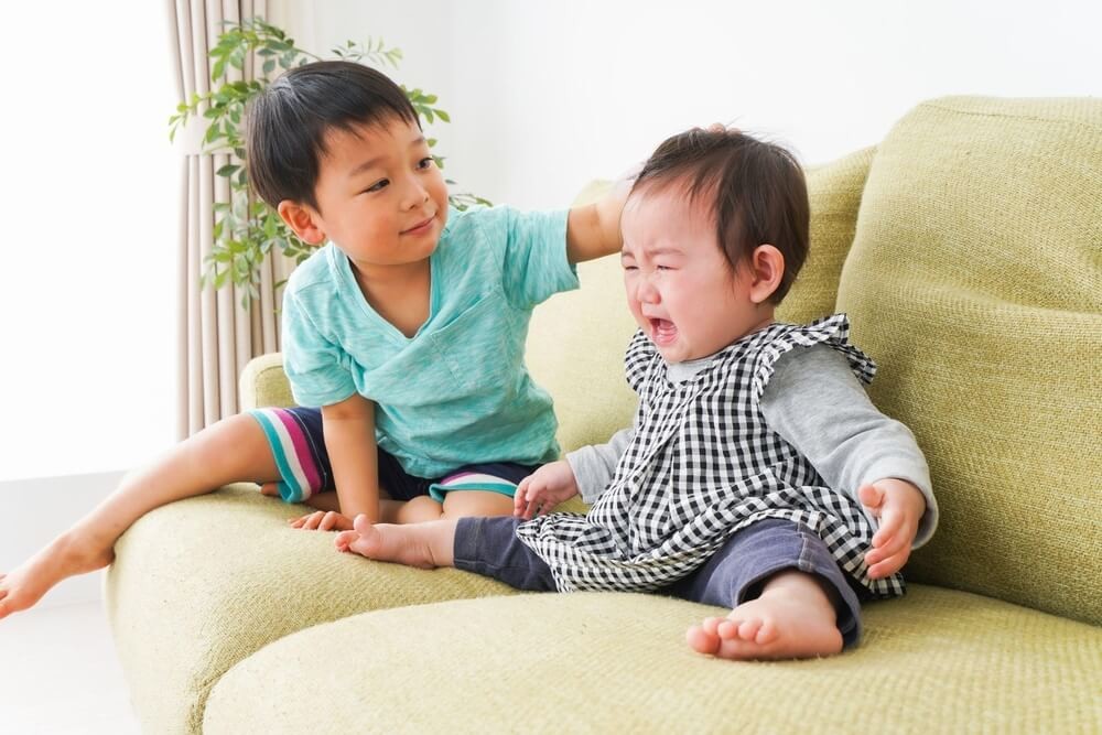 泣いている赤ちゃんをなでる男の子