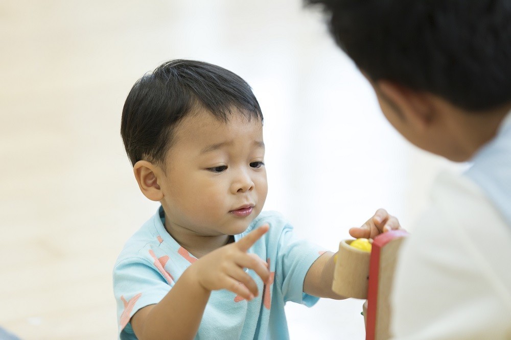 保育士とおもちゃで遊ぶ男の子