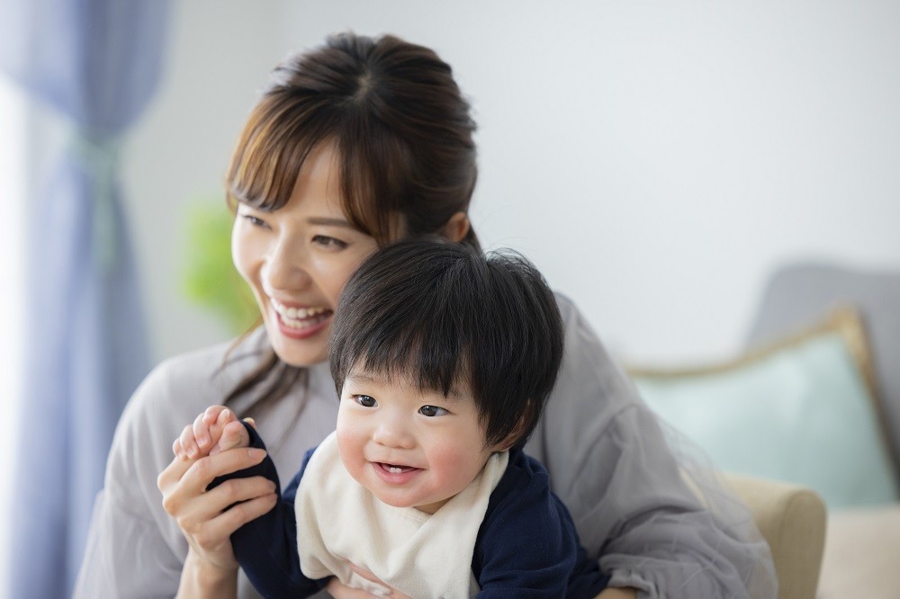 女性の膝に座って笑っている子ども