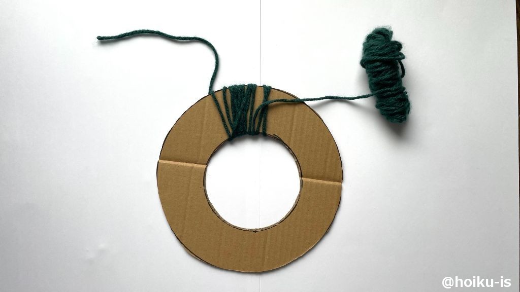 15cmほど毛糸を残して、ダンボールをくぐらせながら毛糸を巻いていく