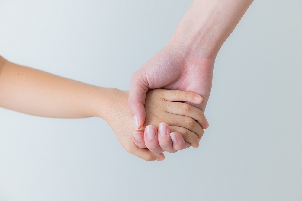 子どもの手を握っている大人の手