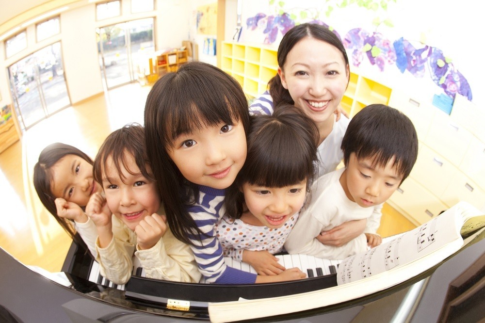 ピアノの椅子に座っている子どもたちと保育士