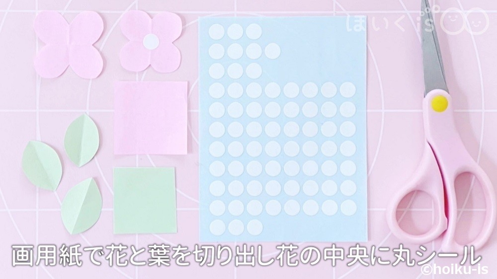 画用紙で花と歯を切り出し花の中央に丸シールを貼っている場面