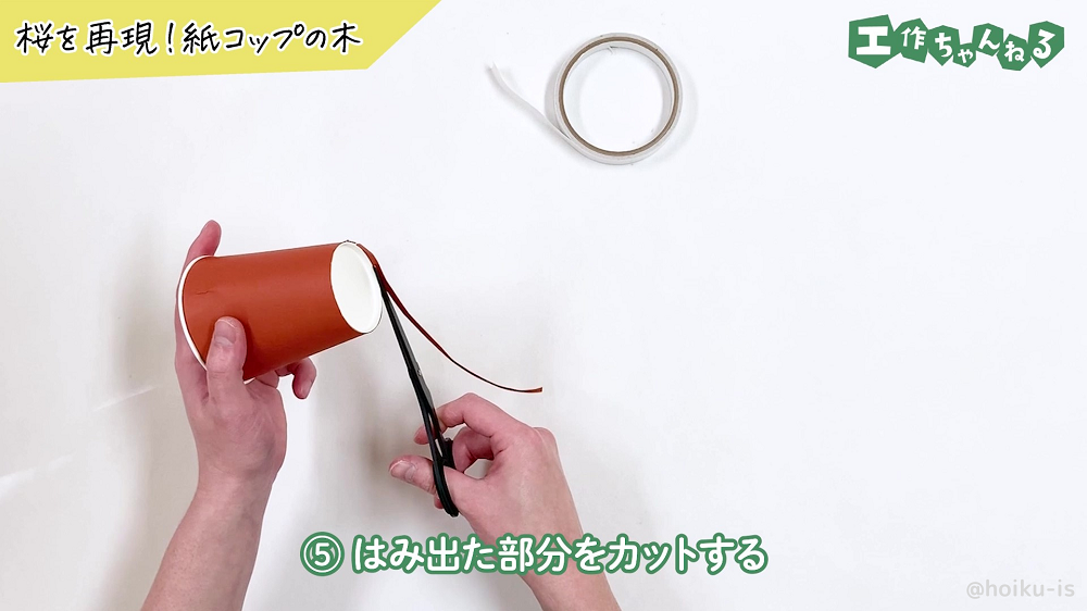 紙コップの底からはみ出た画用紙を切っている様子