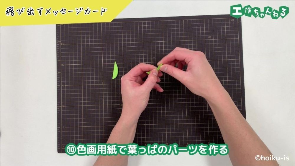 画用紙で作った葉っぱに折り目をつけている手元