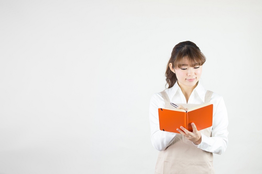 メモ帳に記入をしている保育士