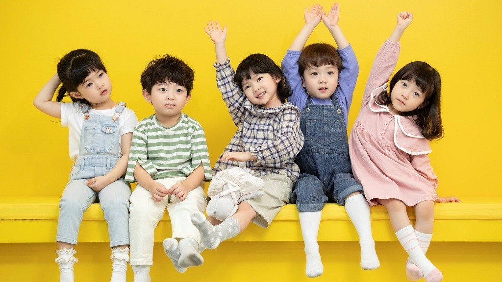 黄色い椅子に並んで座っている5人の子ども