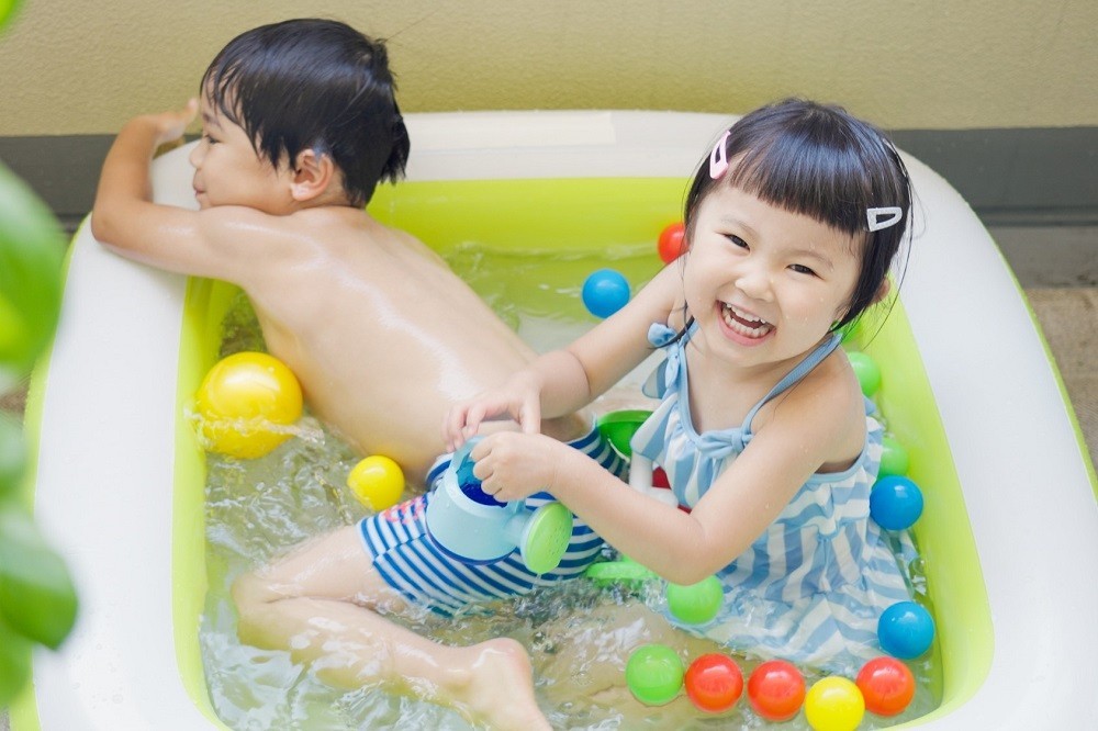 ビニールプールで遊んでいる2人の子ども