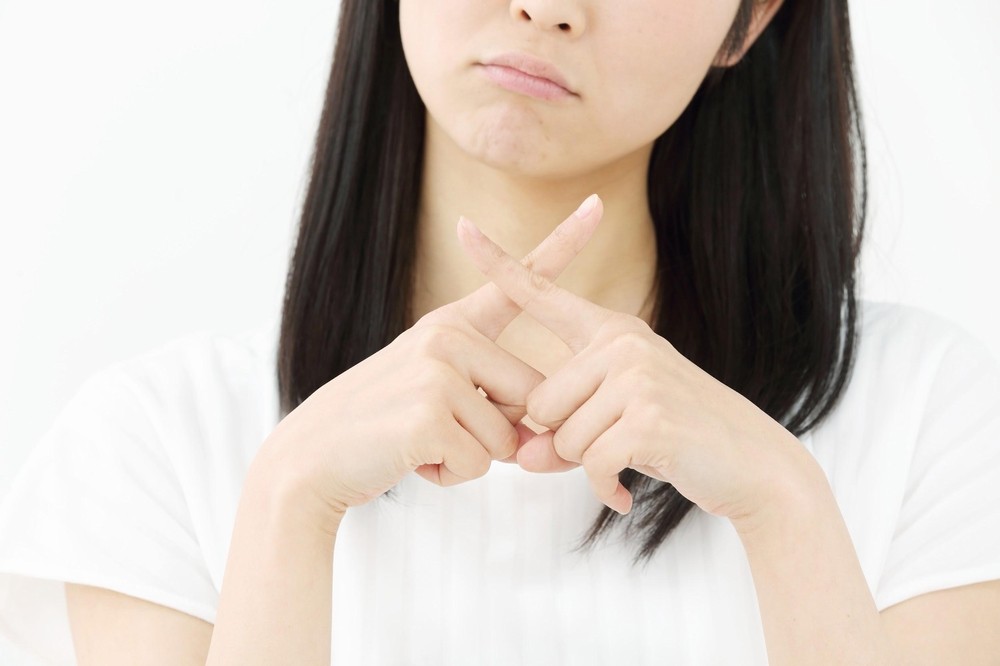 手でバツマークを作っている女性