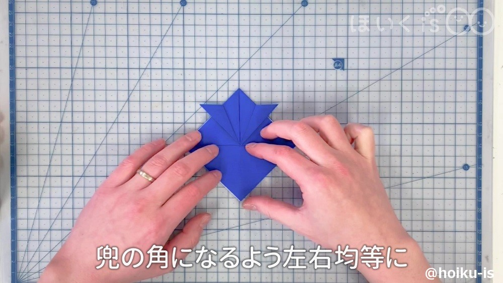 兜の角になるよう左右均等に折っているところ