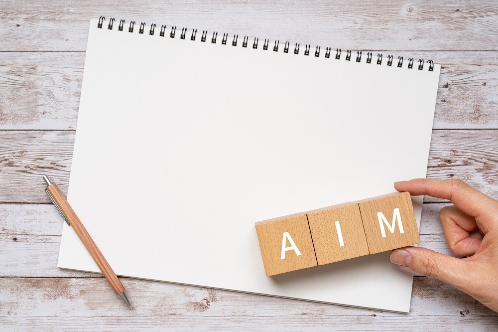 「AIM」と書かれた積み木とスケッチブック