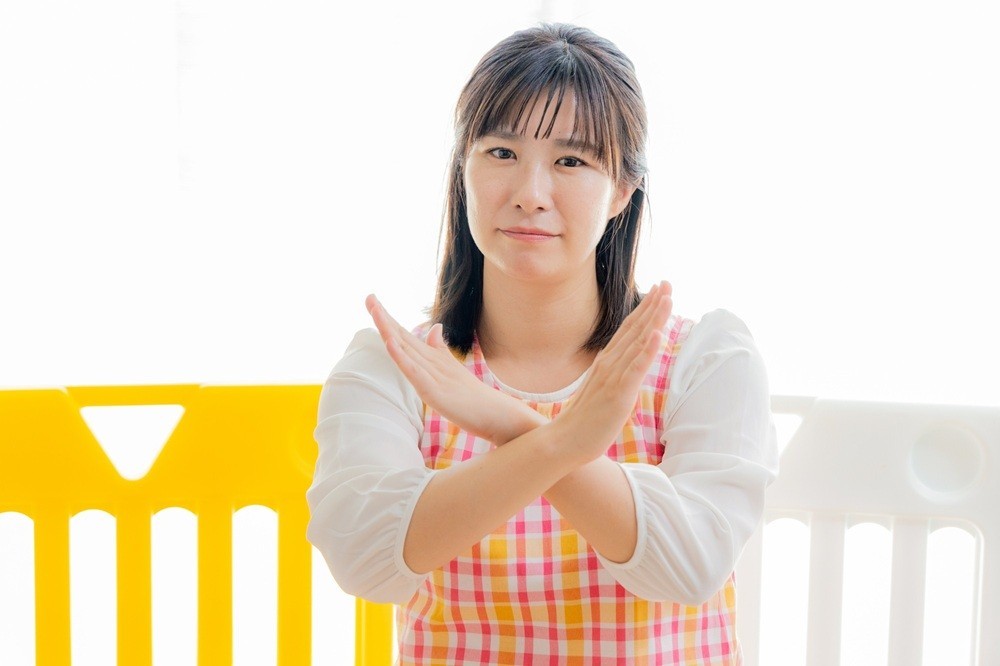 手でバツを作っている保育士