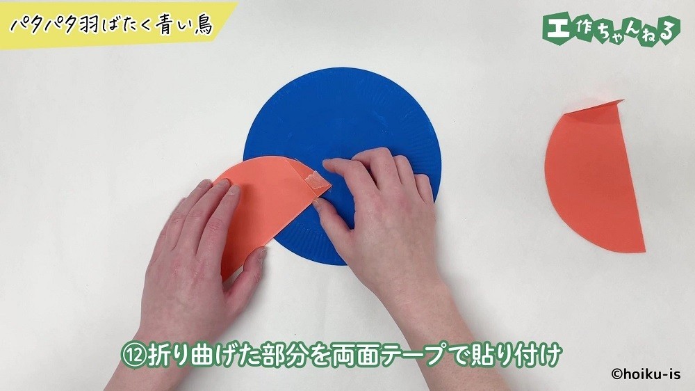 折り曲げた色画用紙に両面テープを貼っている手元