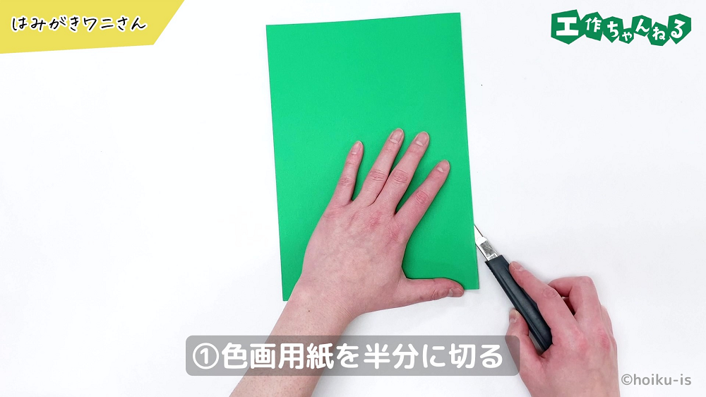 緑の色画用紙を半分に切っている手元
